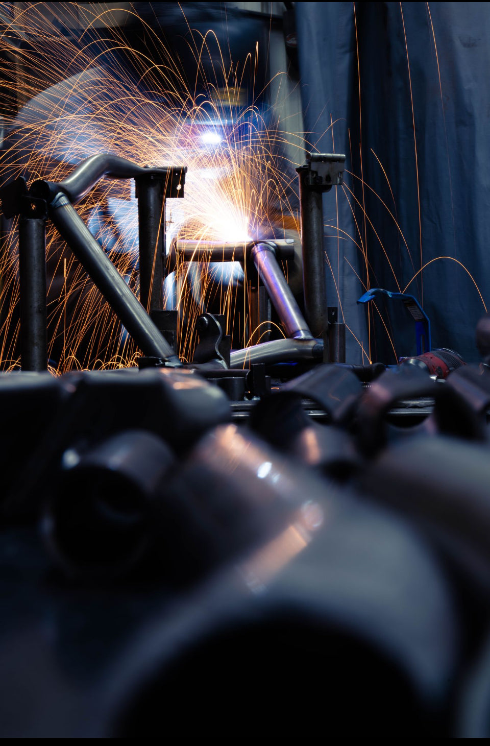 Person welding metal with sparks flying, wearing protective gear.